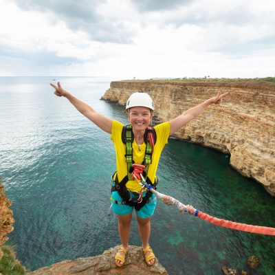 Young,Woman,Jump,From,The,Cliff,With,A,Rope.,Ropejumping