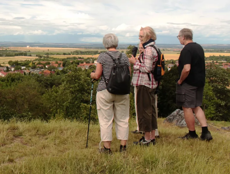 A group of walkers at the top of a hill looking out at the view